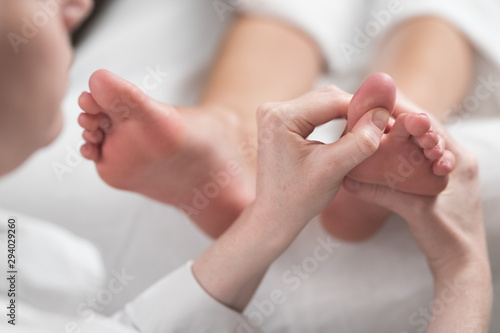 Professional female masseur giving reflexology massage to woman foot. photo