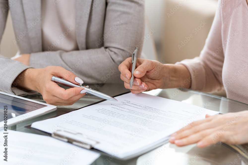 Two businesswomen consulting or discussing terms of contract at meeting Two businesswomen consulting or discussing terms of contract at meeting