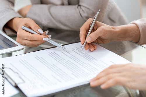 Human hands with pens over financial document in moment of putting signature