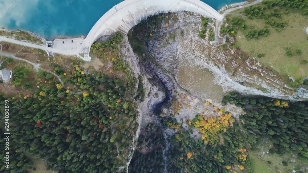 Hydroelectricity generated from water dam and reservoir lake in Swiss Alps mountains to produce renewable energy and limit global warming, sustainable hydropower, aerial drone footage 4K 60fps video
