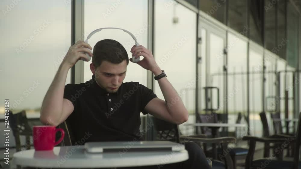 Portrait of a male freelancer. Man is wearing headphones and starting work on notebook at cafe Portrait of a male freelancer. Man is wearing headphones and starting work on notebook at cafe