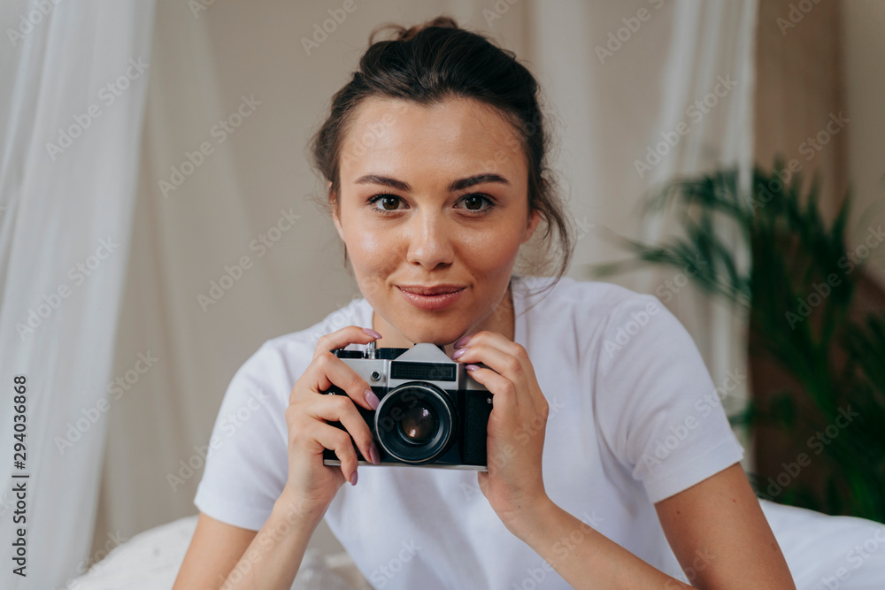 Pretty young woman is holding camera at home