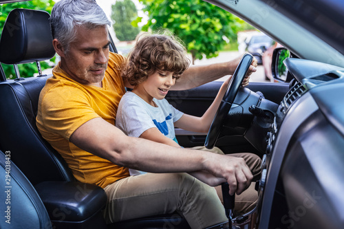 Happy Caucasian man and little boy studying driving vehicle