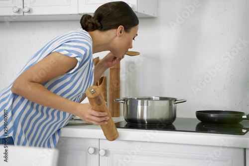 Young woman tasting meal while cooking stock photo