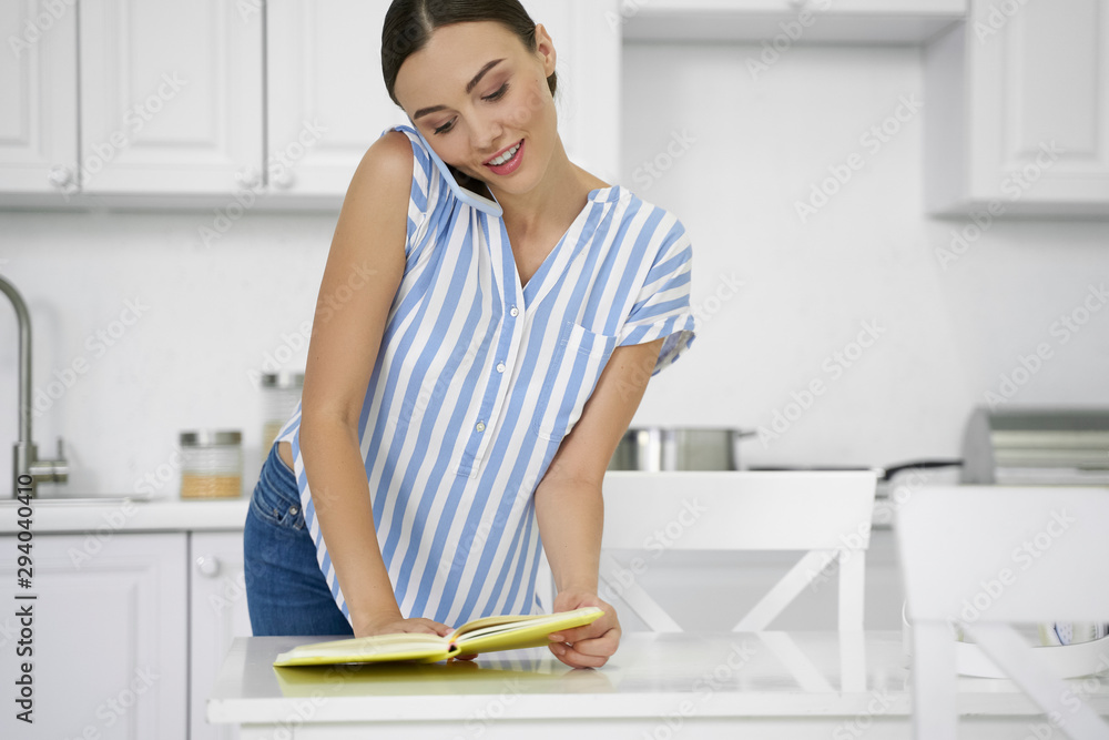 Woman pressing smartphone to shoulder and checking notes stock photo Woman pressing smartphone to shoulder and checking notes stock photo