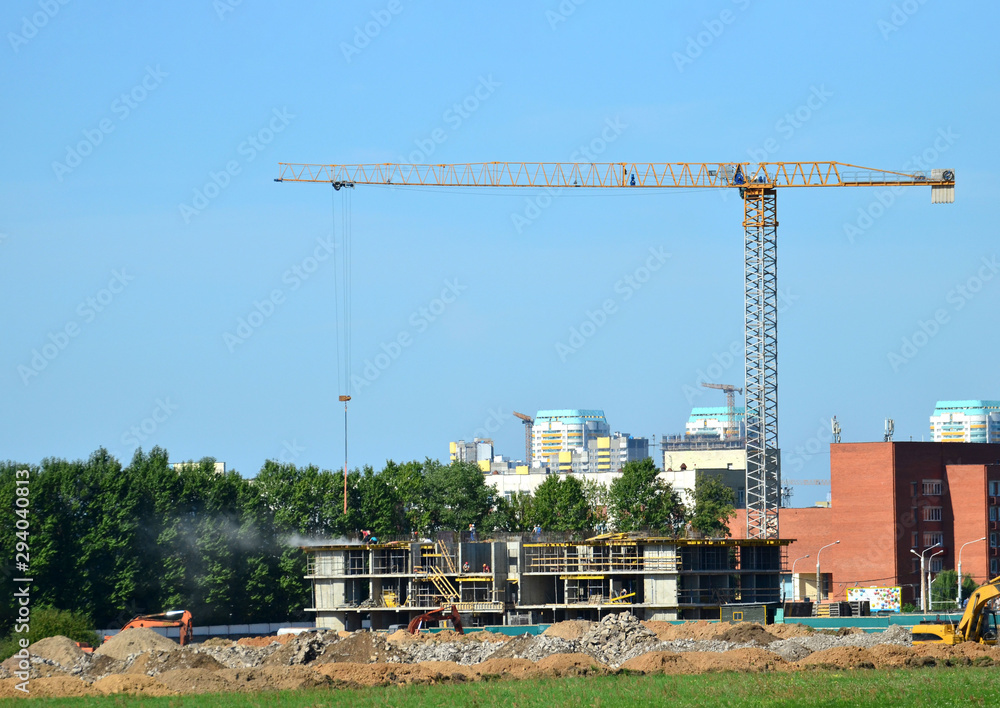 Tower cranes constructing a new residential building at a construction site against blue sky. Renovation program, development, concept of the buildings industry. Tower cranes constructing a new residential building at a construction site against blue sky. Renovation program, development, concept of the buildings industry.