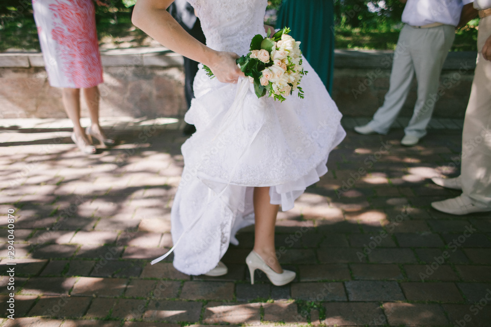 bride's feet in white wedding shoes with a bouquet bride's feet in white wedding shoes with a bouquet