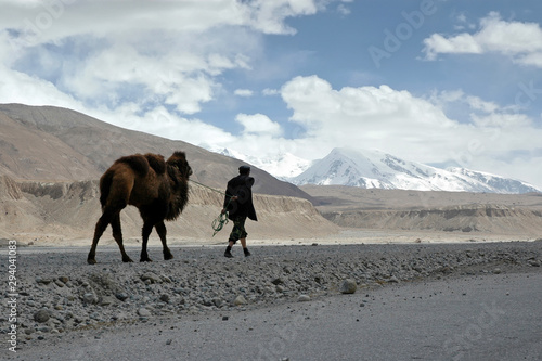 Mountainous landscape. A man with camel in Pamir mountains. Outskirts of Kashgar, Xinjiang, China, Asia.