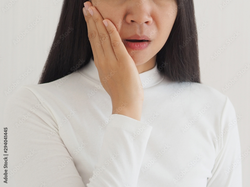 trigeminal neuralgia and temporomandibular joint and muscle disorder in asian woman, She use hand touching her cheek and symptoms fo pain and suffering on isoleted white background. trigeminal neuralgia and temporomandibular joint and muscle disorder in asian woman, She use hand touching her cheek and symptoms fo pain and suffering on isoleted white background.