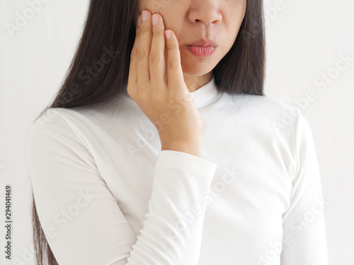 trigeminal neuralgia and temporomandibular joint and muscle disorder in asian woman, She use hand touching her cheek and symptoms fo pain and suffering on isoleted white background.