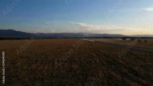 Aerial drone shot of a car on dusty road at sunset