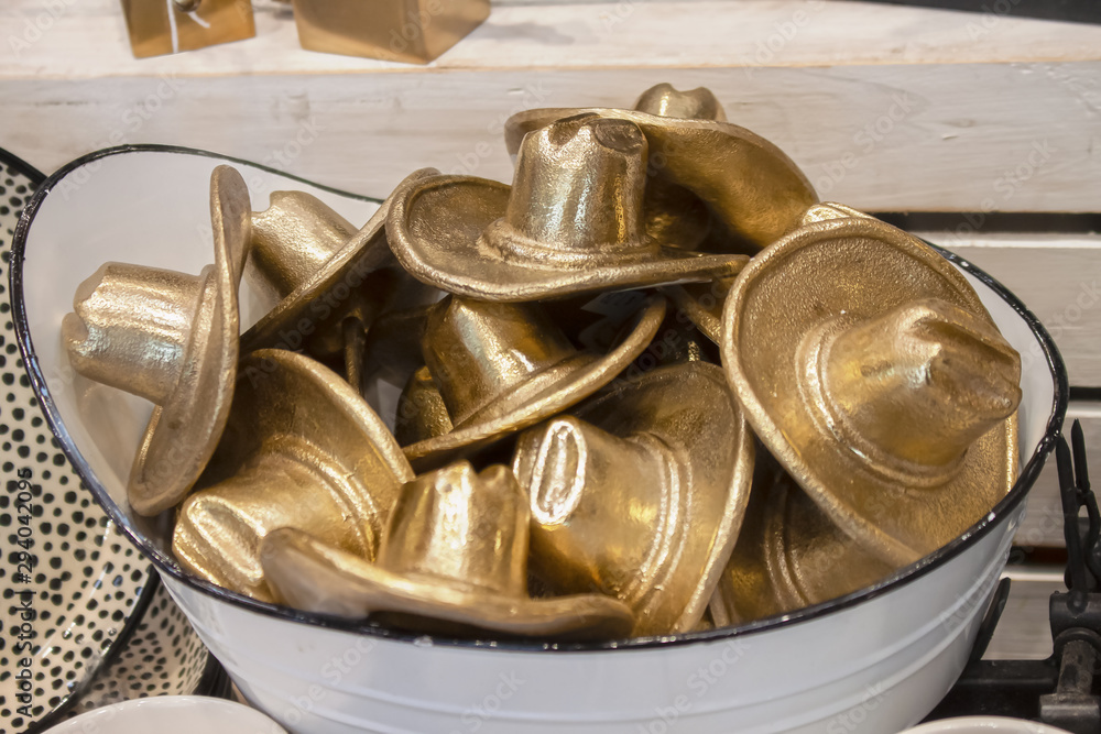 Washtub full of golder metal cowboy hats sitting on wooden shelf - shallow focus