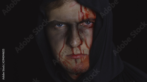 Man executioner Halloween makeup and costume. Guy with blood on his face