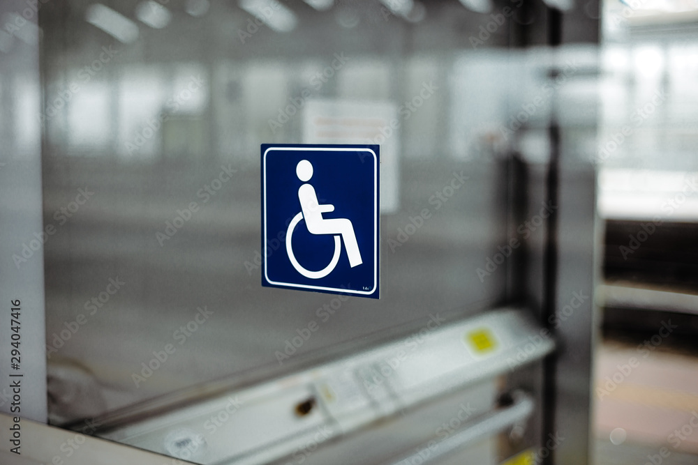 Disabled person's stamp on a blue plate on the elevator. The concept of supporting people with disabilities in the world, facilitating access, help in free movement. Disabled person's stamp on a blue plate on the elevator. The concept of supporting people with disabilities in the world, facilitating access, help in free movement.