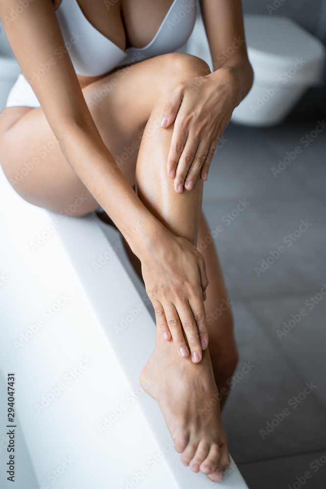 Caucasian woman applying a moisturizing body cream - obrazy, fototapety, plakaty 