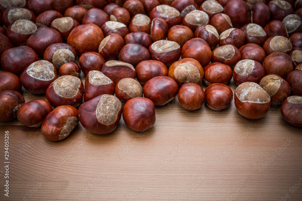 Ripe chestnuts on old wooden table close up with copy space. Raw Chestnuts for Christmas. Ripe chestnuts on old wooden table close up with copy space. Raw Chestnuts for Christmas.