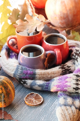 Three cups of coffee  pumpkins  leaves  a woolen scarf on a window background  the concept of home comfort  family  Thanksgiving  autumn season
