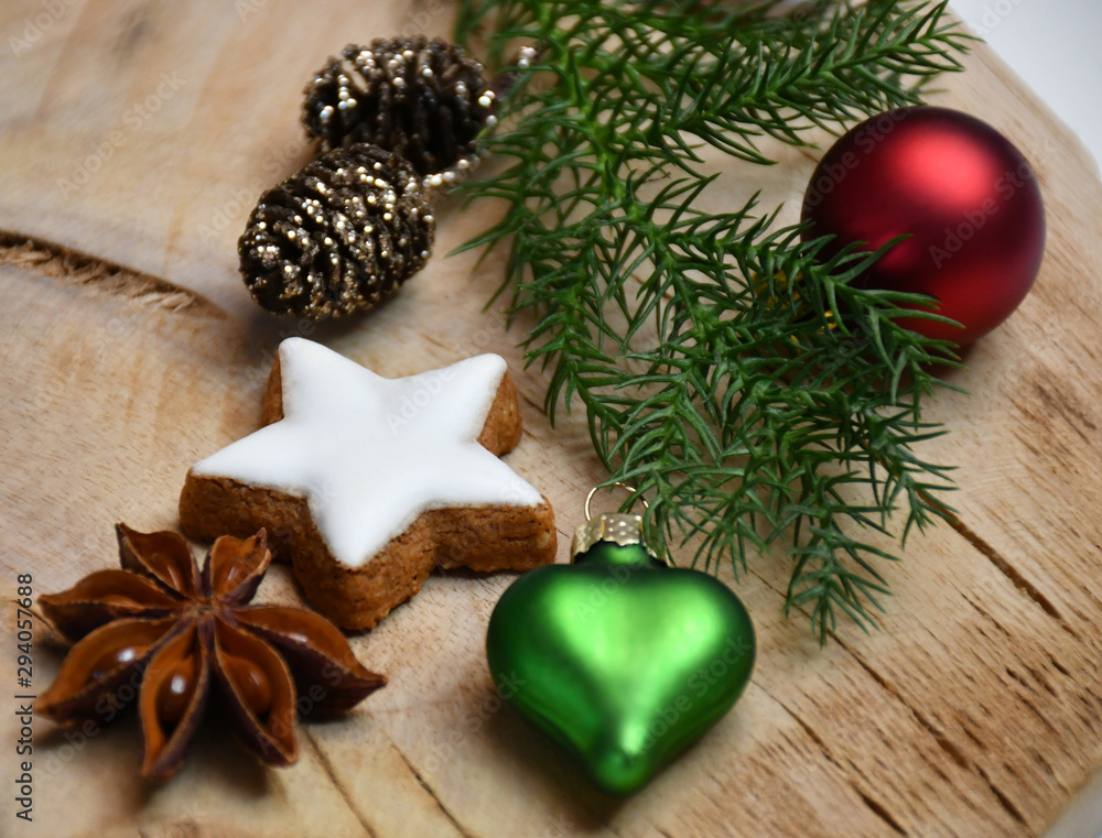 Fototapeta premium A fir tree branch, a star-shaped cookie, a star-anise, cones & Christmas-tree decorations (ball & a heart)