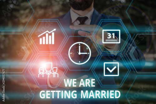 Word writing text We Are Getting Married. Business photo showcasing Engagement Wedding preparation Loving couple Male human wear formal work suit presenting presentation using smart device photo