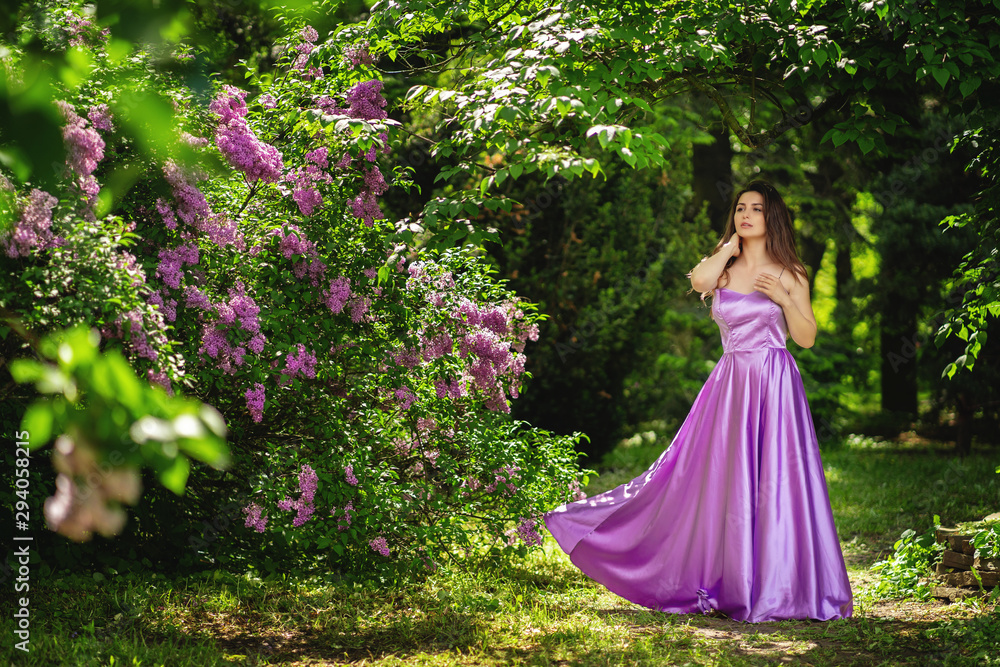 Outdoor summer portrait of young beautiful happy woman in park or at nature. Joyous happy girl in purple dress