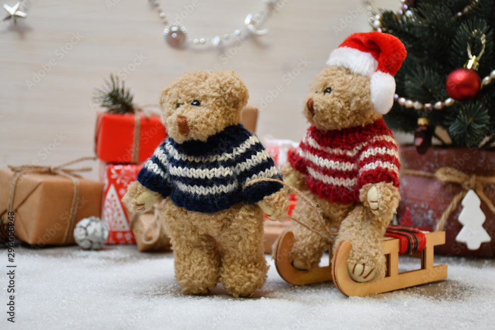 A Teddy Bear takes another one for a sledge drive on a background of a Christmas tree & boxes with Christmas presents A Teddy Bear takes another one for a sledge drive on a background of a Christmas tree & boxes with Christmas presents