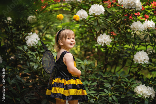 Cute toddler girl playing with flowers in spring park on the walk, wearing funny outfit
