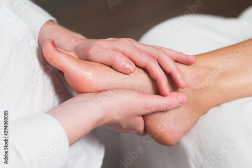 Professional female masseur giving reflexology massage to woman foot. photo