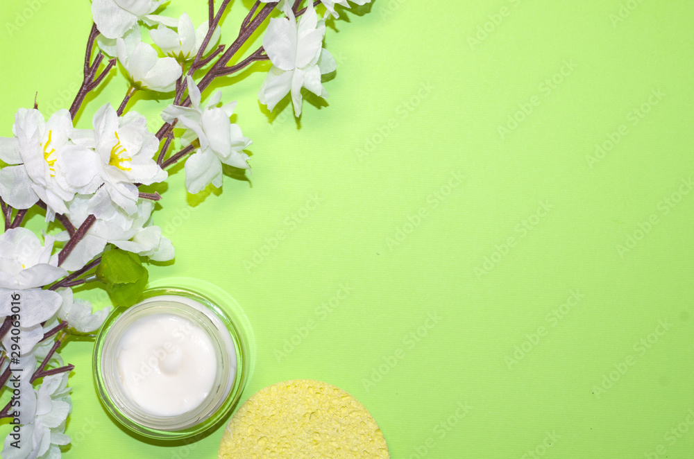 Beautiful composition with cosmetics on light green background, flat lay with skin cream and wthite flowers, spring background with a copy space for an your text, clean beauty concept, top view Beautiful composition with cosmetics on light green background, flat lay with skin cream and wthite flowers, spring background with a copy space for an your text, clean beauty concept, top view