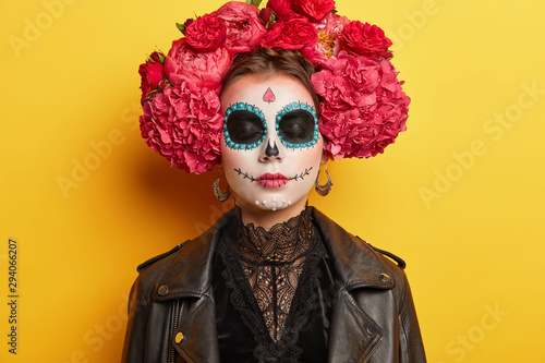 Traditional holiday in November. Female with sugar skull drawn with smile, wears flower wreath, dressed in black clothes, remembers death of ancestors, visits cemetery. Reuniting of living and dead