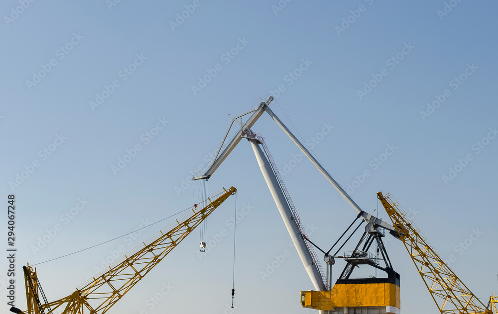 Yellow construction cranes close-up. Blue sky and white clouds. Place for text. Selective focus image. Copy space.