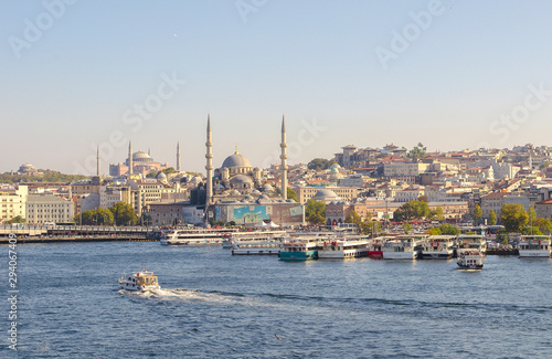 Touristic boats in Golden Horn bay of Istanbul and view on Suleymaniye mosque. View of old city, mosque, red tile roofs and green trees. Clear blue sky. Turkey, Istanbul