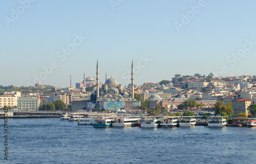 Touristic boats in Golden Horn bay of Istanbul and view on Suleymaniye mosque. View of old city  mosque  red tile roofs and green trees. Clear blue sky. Turkey  Istanbul