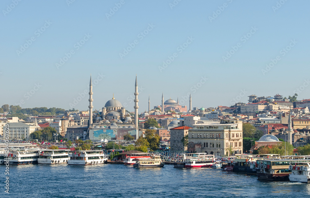 Touristic boats in Golden Horn bay of Istanbul and view on Suleymaniye mosque. View of old city, mosque, red tile roofs and green trees. Clear blue sky. Turkey, Istanbul