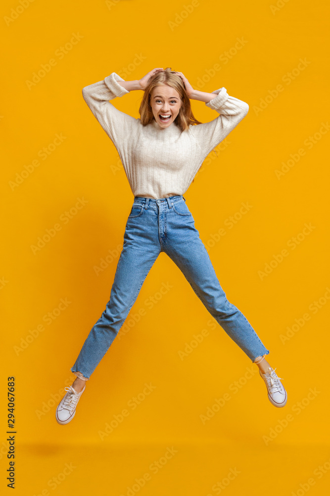 Excited girl jumping in air with hands on head Excited girl jumping in air with hands on head