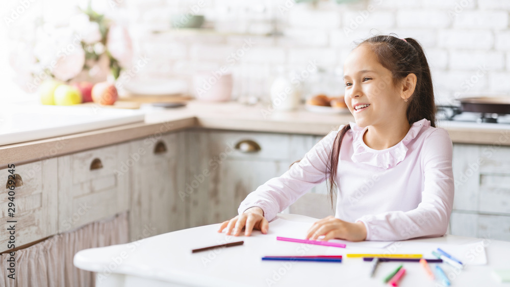 Adorable little girl sitting at kitchen table and smiling Adorable little girl sitting at kitchen table and smiling