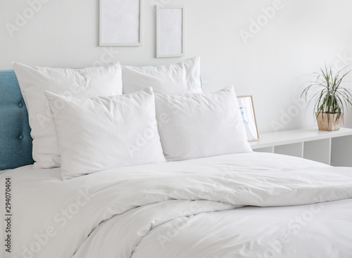 White pillows and duvet on the blue bed. White pillows, duvet and duvet case on a blue bed. White bed linen on a blue sofa. Bedroom with bed and bedding and poster frame mock up on the wall.Front view photo