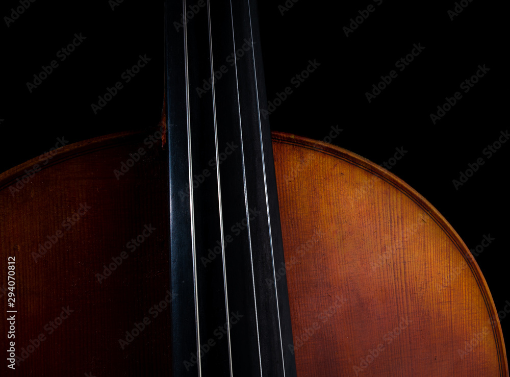 Close up high resolution photo of a cello, showing strings, body, and upper bout isolated against a black background Close up high resolution photo of a cello, showing strings, body, and upper bout isolated against a black background