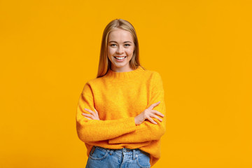 Beautiful young girl posing to camera with folded arms