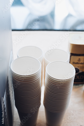 Stacks of white plastic or paper takeaway cups in piles.
