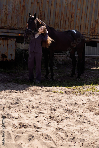 photo beautiful woman in a suit standing next to his horse