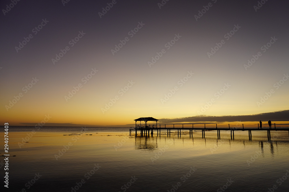 Two people watch a sunset from a pier leading into a lagoon on the island of Fakarava in French Polynesia
