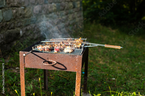 Grilled kebab cooking on metal skewer. Roasted meat cooked at barbecue.Traditional eastern dish, shish kebab. Grill on charcoal and flame, picnic, street food