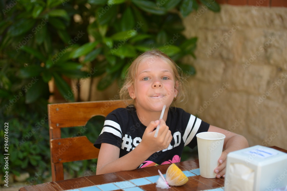 Little girl drinks milk cocktail in a street cafe. Summer holiday