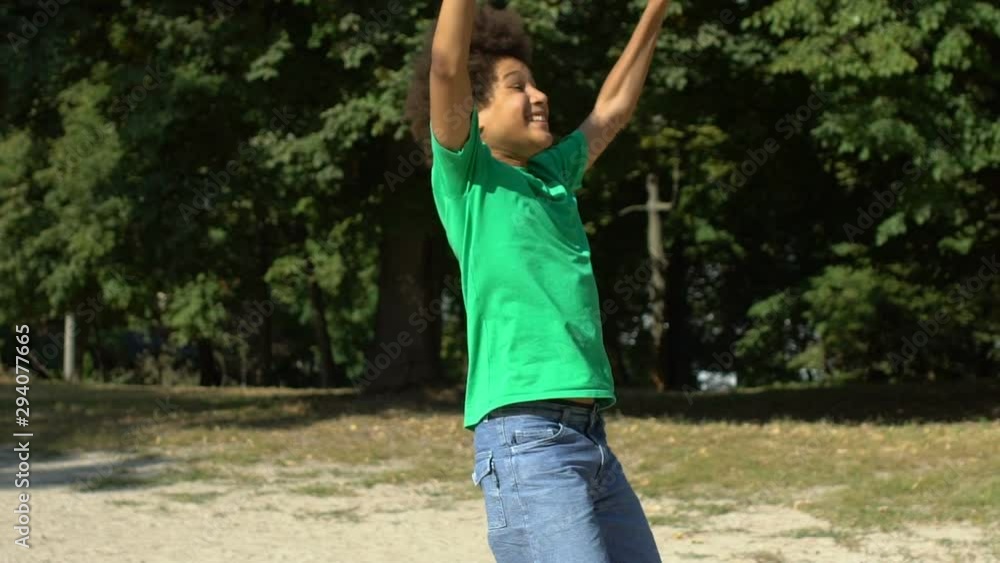 Excited african teenager showing yes gesture running park, winning competition