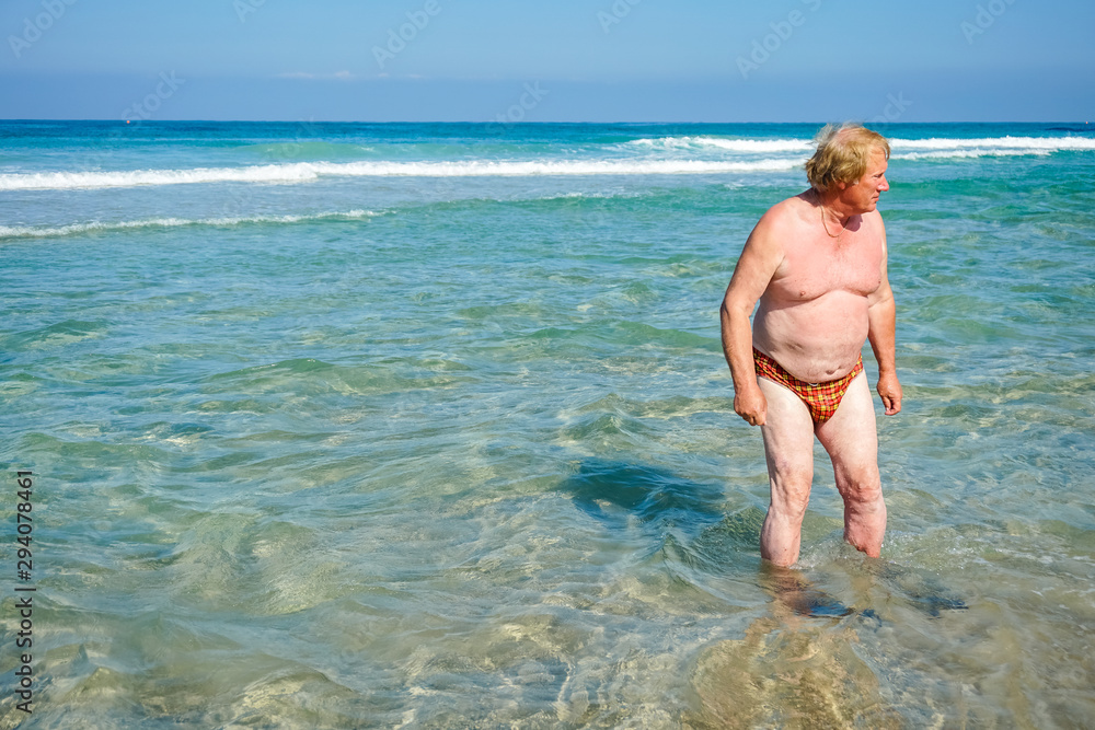 An elderly man with flippers resting on the beach An elderly man with flippers resting on the beach