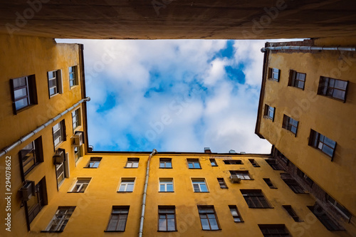 Saint Petersburg. Russia. Architecture. Yards-wells in the center of St. Petersburg. The yard is bounded by closely spaced walls of houses. Yellow buildings against the sky and clouds. Petersburg sky