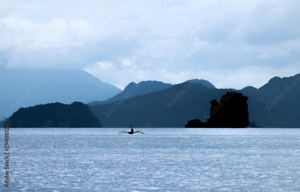 Serene shot of a Man in a Kayak with Philippine Islands in the Background Serene shot of a Man in a Kayak with Philippine Islands in the Background