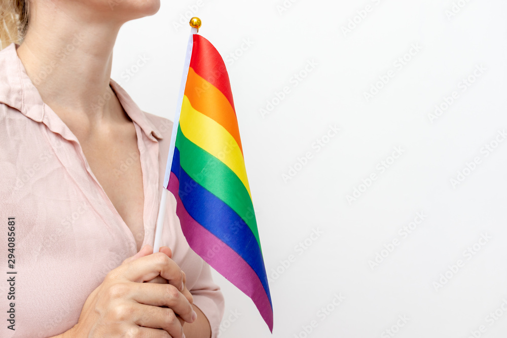 Lesbian woman holding an lgbt rainbow flag in hands as a simbol of freedom and gender equality with copy space Lesbian woman holding an lgbt rainbow flag in hands as a simbol of freedom and gender equality with copy space