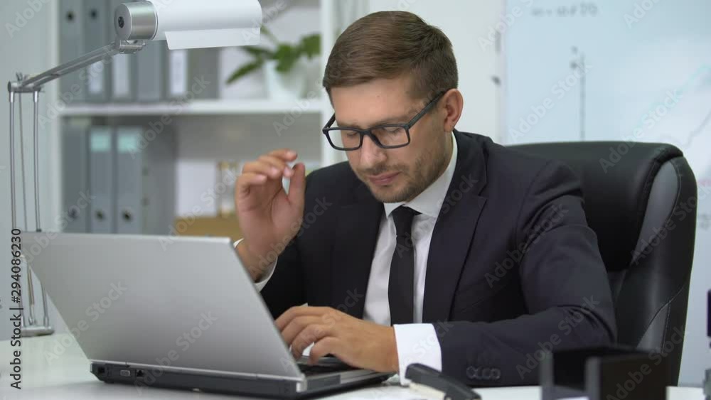 Man in business suit typing on laptop pc, feeling eye tension taking off glasses Man in business suit typing on laptop pc, feeling eye tension taking off glasses