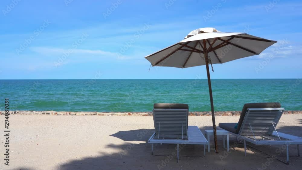 Two beach chairs on tropical beach, shaded by tall umbrella. Gentle breeze. Two beach chairs on tropical beach, shaded by tall umbrella. Gentle breeze.